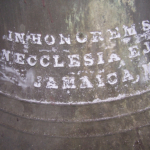 A metal bell with writing on it.