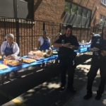 A police officer standing next to a table with food.