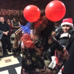 A woman wearing a dress with red balloons on her head.