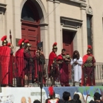 A group of people in red costumes standing on a balcony.