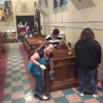 A group of people cleaning the pews in a church.