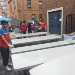 A group of people cleaning tables in a parking lot.