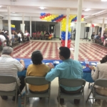 A group of people sitting at tables in a room with balloons.