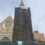 A church tower with scaffolding in front of it.