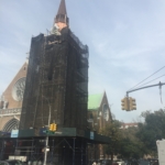 A church with a steeple in the middle of a street.