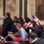 A group of people in a church holding flags.