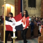 Two people holding a dominican flag in a church.