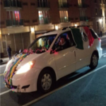A white car decorated with mexican flags on the street.