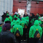 A group of people in green hoodies standing in front of a church.
