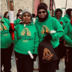 A group of women in green hoodies holding a torch.