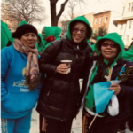 Three women in green hoodies posing for a photo.