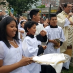 A priest holding a tray in front of a crowd of people.
