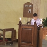 A boy is standing at a podium in a church.