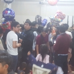 A group of people standing in a room with balloons.
