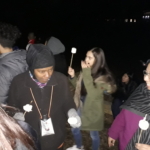 A group of people holding marshmallows at night.