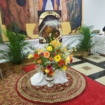 A church with flowers on the floor and a painting on the wall.