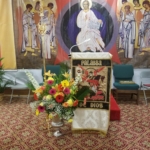 A church is decorated with flowers and a statue of jesus.