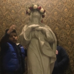 Two children standing next to a statue of the virgin mary.