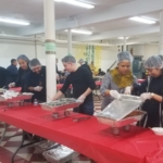 A group of people serving food in a large room.