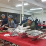 A group of people preparing food in a large room.