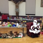 Santa claus sitting in front of a table with stuffed animals.