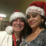 Two women in santa hats standing next to each other.