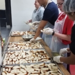 A group of people preparing bread in a kitchen.