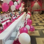 A pink and white party with balloons and tables.