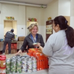 A group of people standing around a table with cans of food.