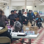 A group of people standing in line at a food pantry.