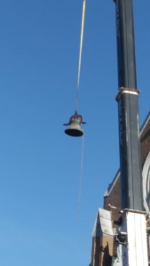 A bell hanging from the side of a building.
