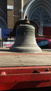 A bell with a cross on it in front of a building.
