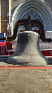 A large bell sitting on top of a cement floor.