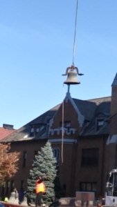 A bell hanging from the side of a building.