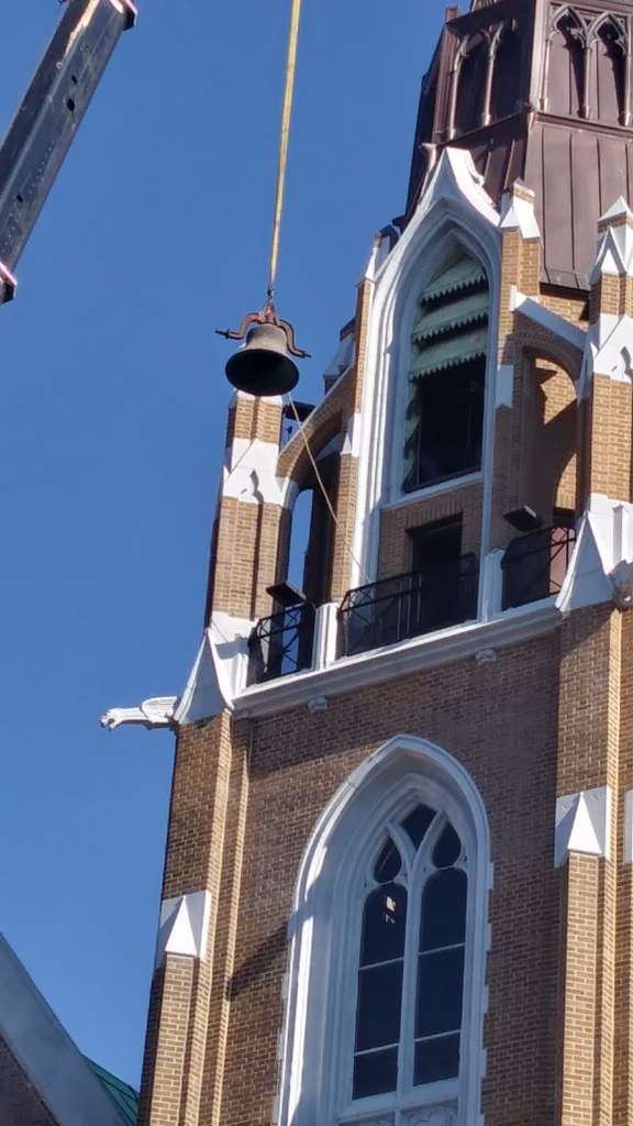 A bell hanging from the side of a church.