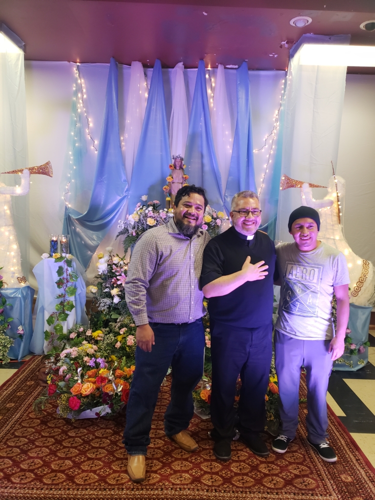 Three men posing for a picture in front of a christmas tree.