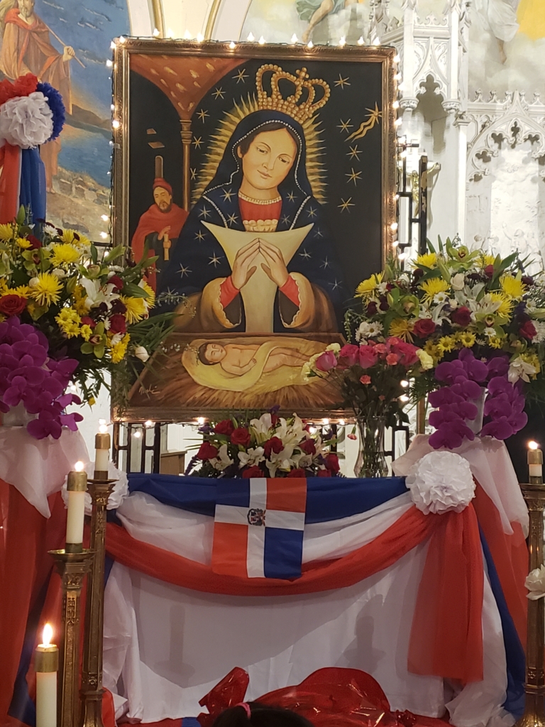 A picture of the virgin mary in front of flowers.