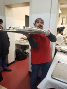 A man holding a tray of food in the kitchen.