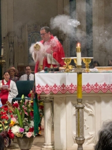 A priest is blowing smoke from the altar.