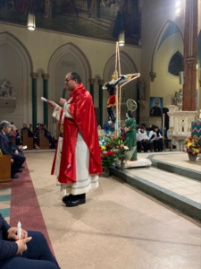 A priest is wearing red and white in the church.