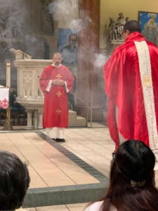 A priest is standing in front of people.