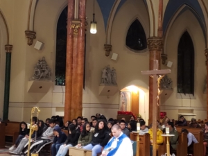 A large group of people sitting in front of a cross.