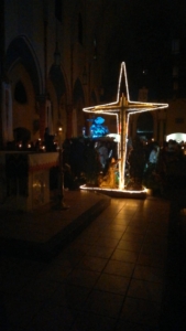 A cross with lights on it in the middle of an indoor area.