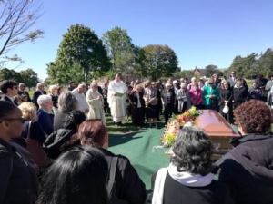 A crowd of people standing around a casket.