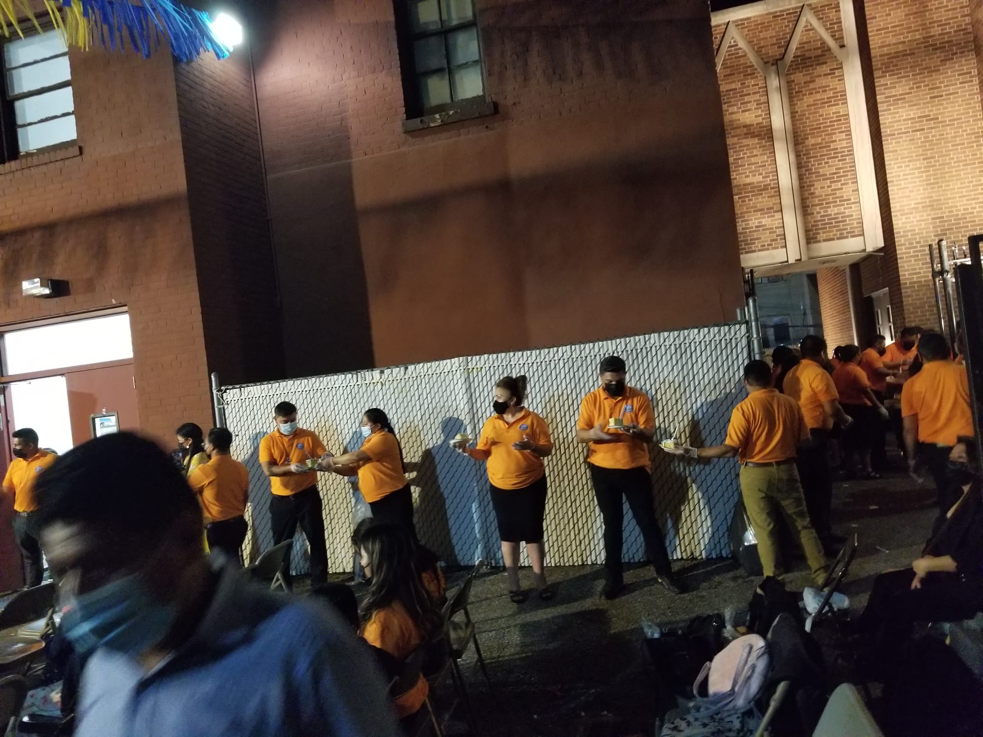 A group of people in yellow shirts standing on the side of a building.