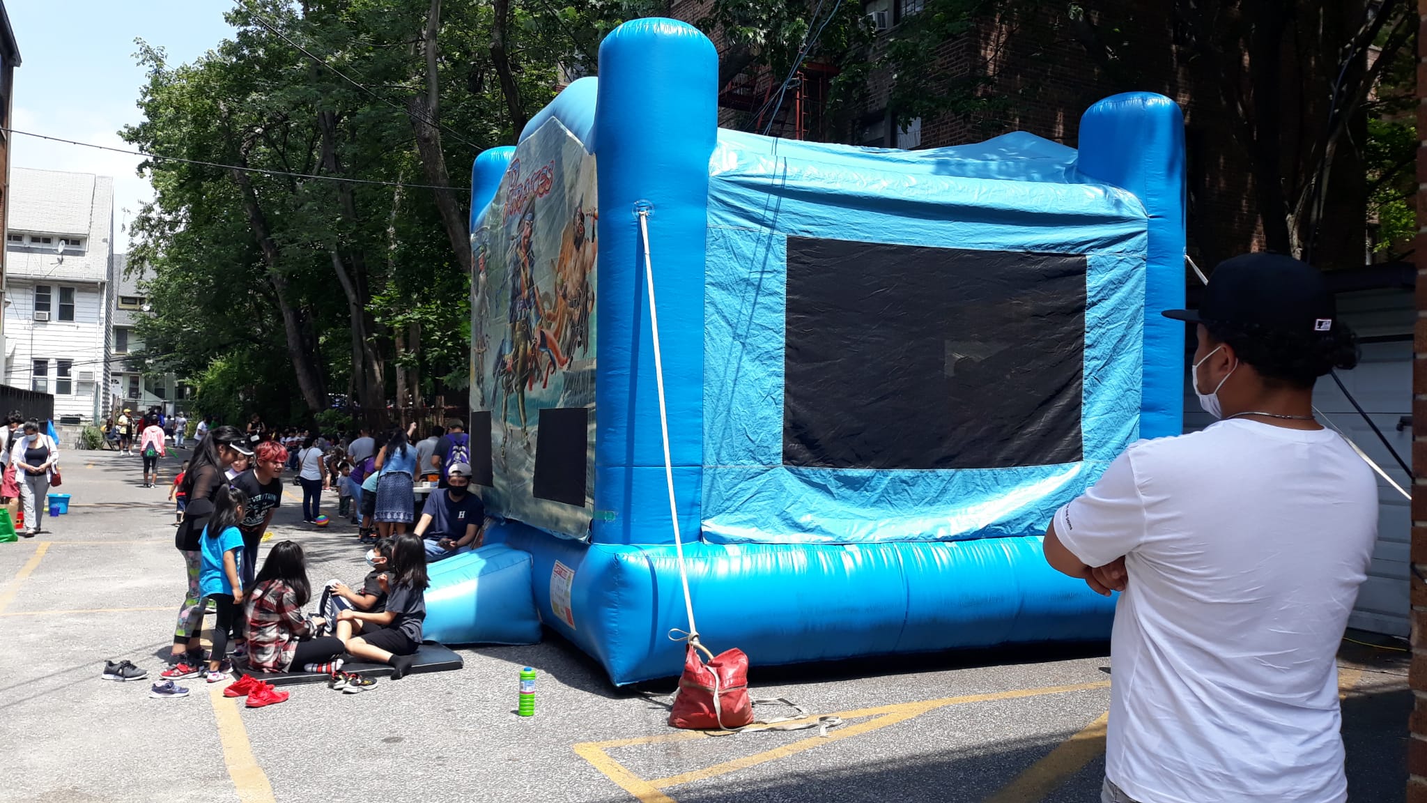 A blue inflatable bounce house with people sitting on it.