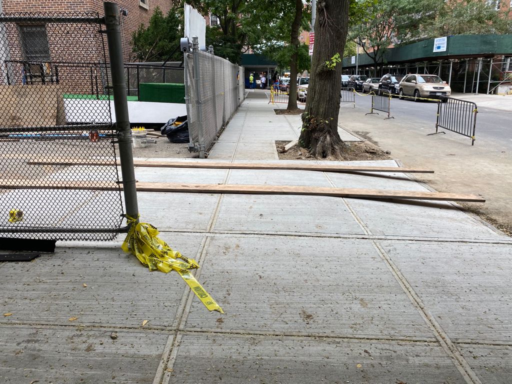 A yellow tape is on the ground near a fence.