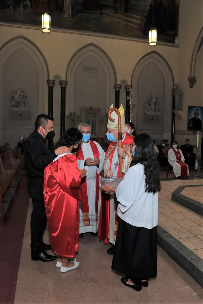 A group of people standing around in front of a priest.