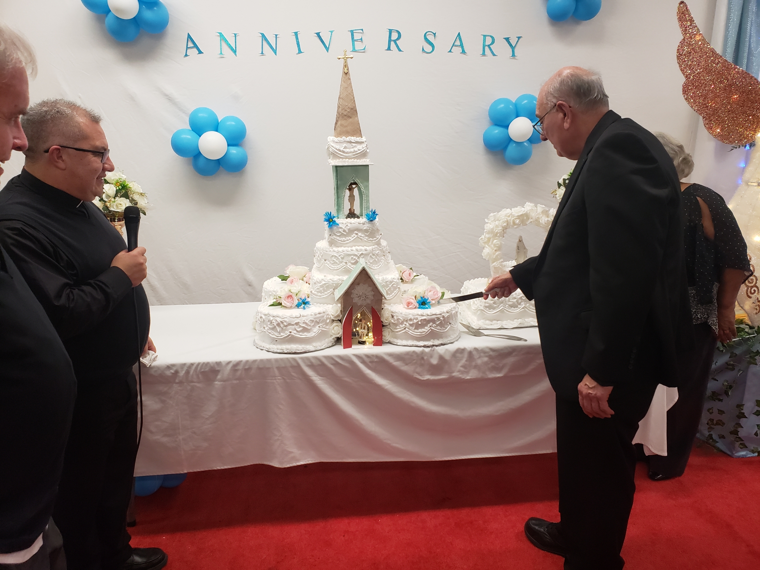 A couple of people standing in front of a cake.
