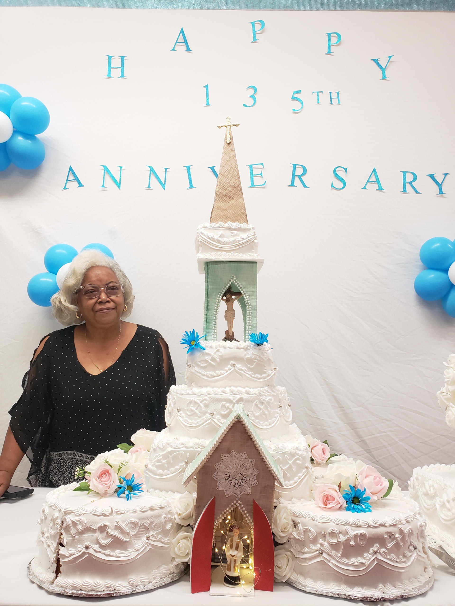 A woman standing next to a cake with a picture of a wedding.